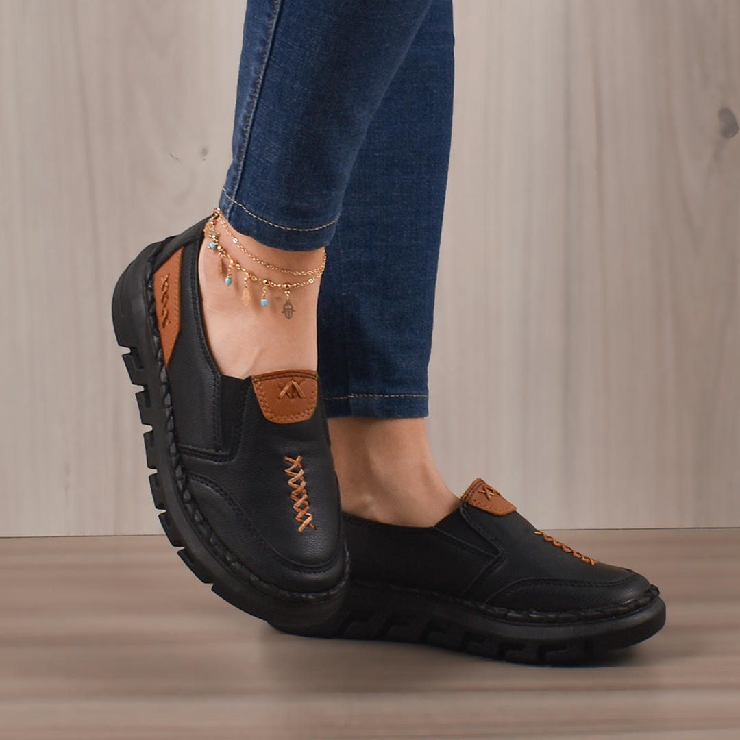 Mocasines Bellami negros de cuero con suela gruesa de goma, detalles marrones y cordones decorativos laterales.
